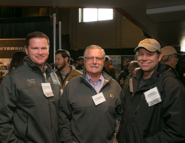 Three men standing together and smiling