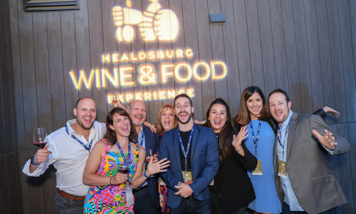 People posing in front of the Healtsburg Wine and Food Experience sign