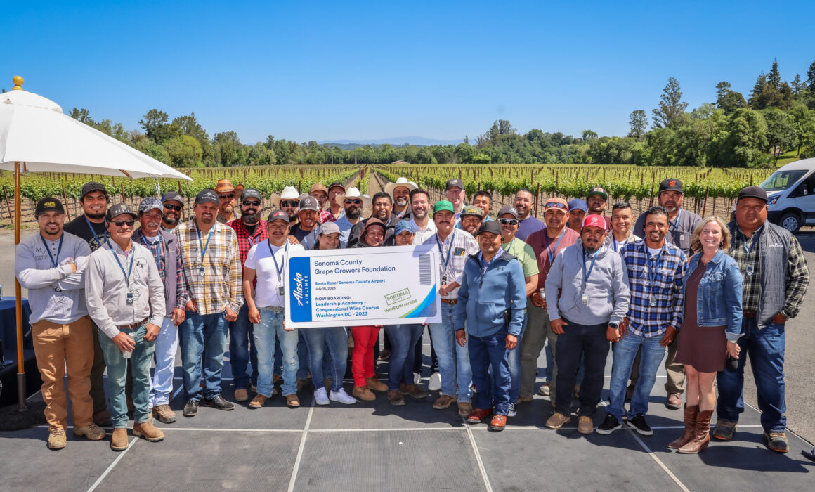 Large group of people holding a "ticket" to the Sonoma County Grape Growers Foundation