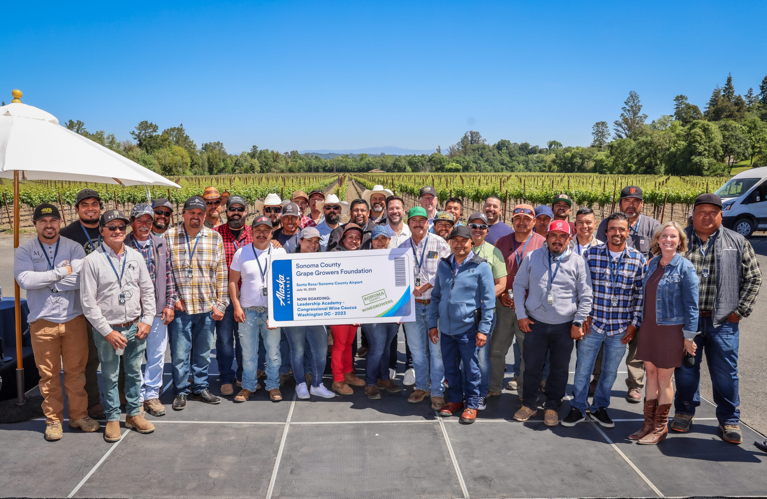 Large group of people holding a "ticket" to the Sonoma County Grape Growers Foundation