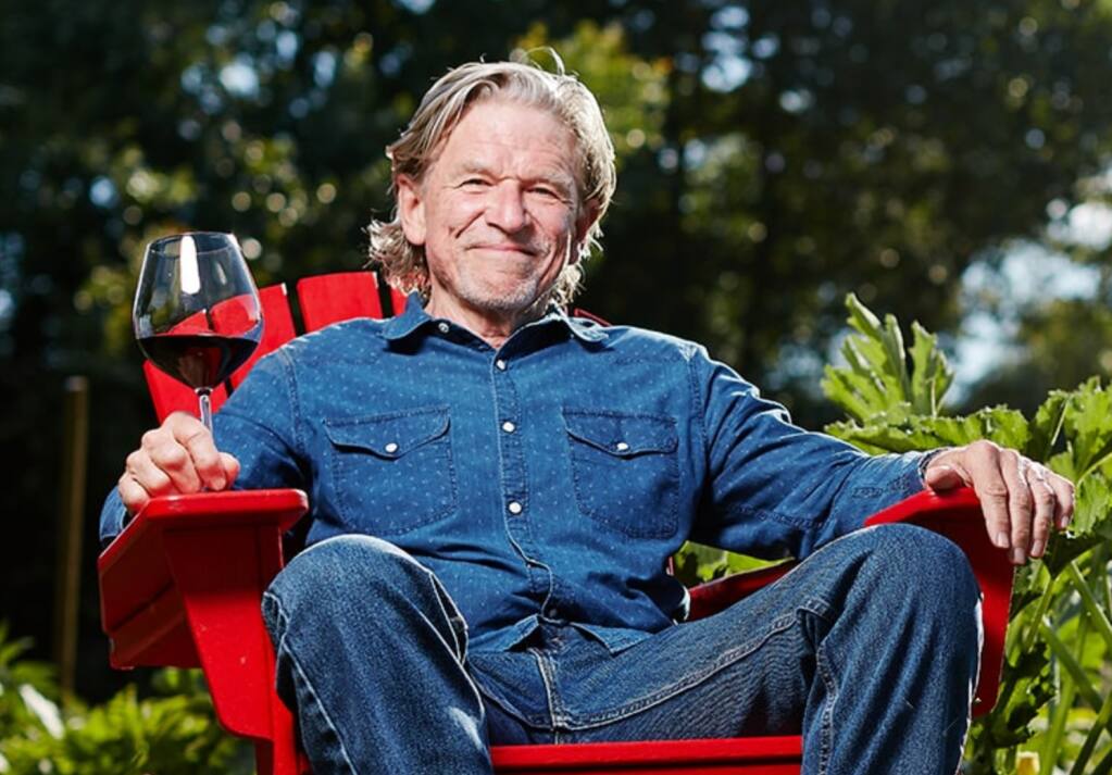 Man sitting on a red Adirondack chair with a glass of wine